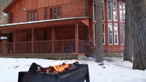 Panoramic video of open fire in iron brasier barbecue with cottage on winter background : vidéo de stock