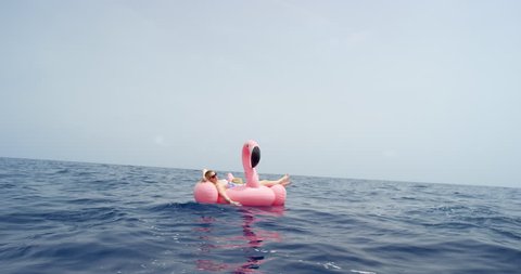 Woman lying on inflatable flamingo floating in middle of ocean girl relaxing in summer sunshine enjoying tropical vacation