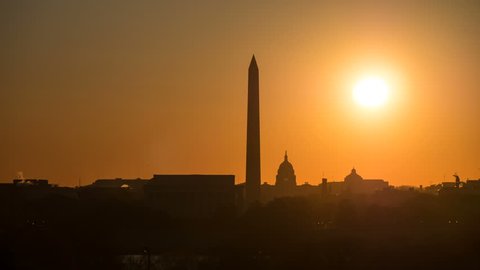 (Time-lapse) The sun rises over the skyline including the Lincoln Memorial, Washington Monument and US Capitol building near the spring equinox in Washington, DC. See separate clip without lens flare.
