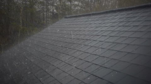 Slow motion of hail hitting home roof in thunderstorm. Roof damage from hail hitting shingles on home roof. Thunderstorm cause damage to house. 
