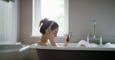 Beautiful Woman listening to music in bathtub enjoying relaxing bubble bath lifestyle real natural body care