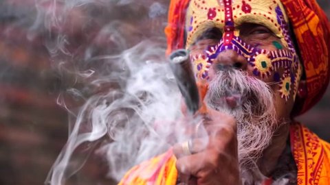 Portrait of sadhu (religious ascetic or holy person) smoking pipe with marijuana. Pashupatinath temple complex that is on UNESCO World Heritage Sites's list Since 1979. Kathmandu, Nepal.