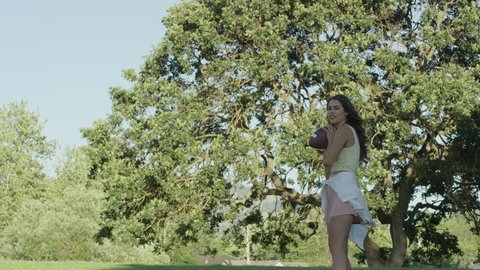 Young Brunette Laughs and Throws Around Football with Friend in Slow Motion Vídeo Stock