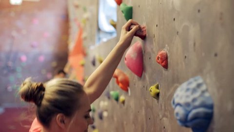 fitness, extreme sport, bouldering, people and healthy lifestyle concept - young woman exercising at indoor climbing gym wall