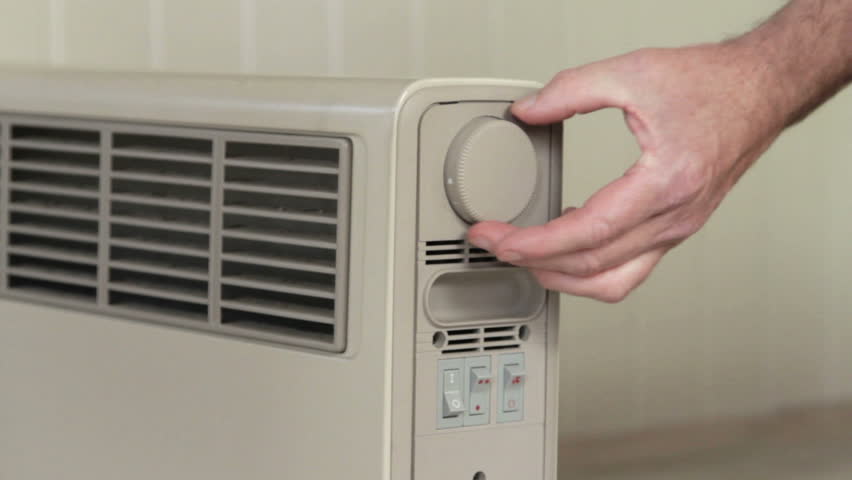 Hand turning electric heating radiator on and thermostat up to maximum | Shutterstock HD Video #2538275