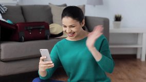 vacation, tourism, travel and people concept - happy young woman with smartphone having video chat at home
