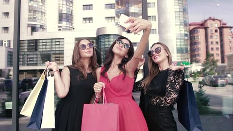 Three pretty girls-shopaholic make selfie after shopping