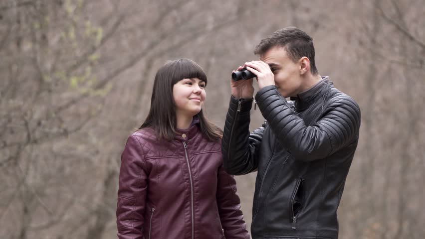 Teenagers having fun outdoor, looking through binoculars for birds in the forest
