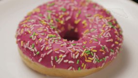 donut with colorful sprinkles on a plate. video rotation