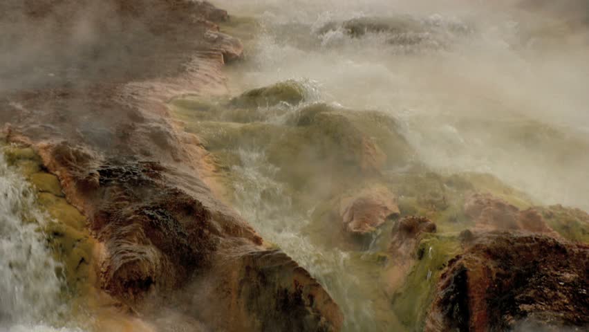 Hot springs water flowing down into river with lots of steam 
