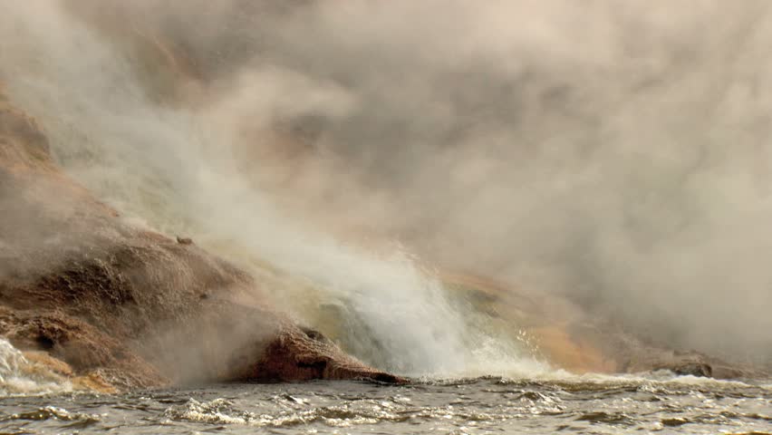 Hot springs water flowing down into river with lots of steam 