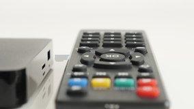 Close-up of STB TV device and infrared remote on white background 4K 2160p 30fps UltraHD video - Tilting on black set-top-box with IR controller 3840X2160 UHD footage