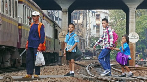 BANGKOK, THAILAND - MARCH, 2017: scavenger and family returning from school awaiting the passage of the train near Hua Lampong train station in Bangkok, Thailand on March, 2017.