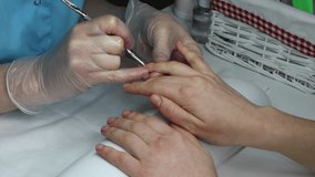 Cleaning of cuticles on female fingers. Woman in a nail salon receiving manicure