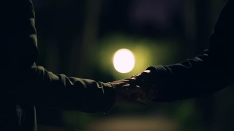 Hand to hand drug transacation at night,suspicious activity.The hands of two men do a ceremonial exchange of an illegal substance on a dark city park at night 50fps slow motion