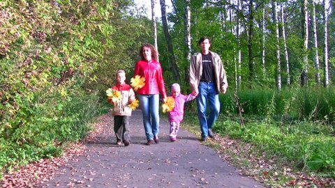 family of four walking in autumn park 