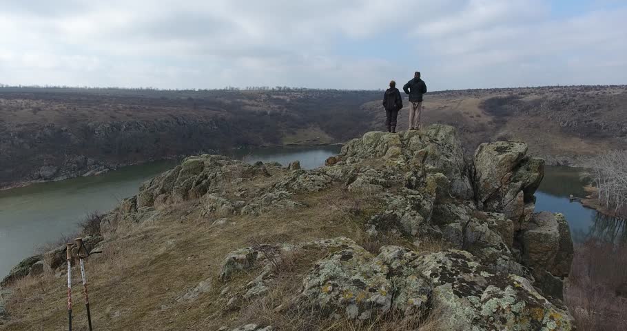 Aerial view two mature tourists rejoice at dawn on the edge of large canyon