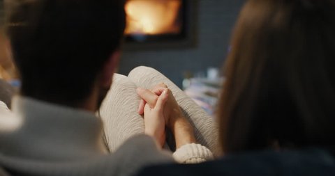 Romantic couple by the Cozy Fireplace. Man and Woman relax by warm fire and warming up their feet. Close up. Winter and Christmas holidays Hygge concept