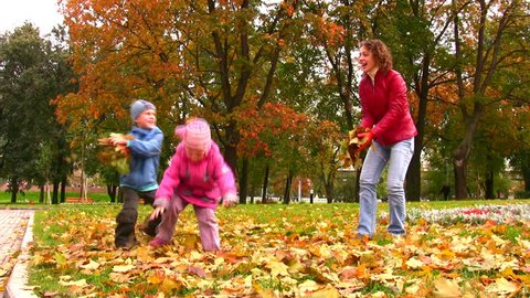 mother with children throw autumn leaves 