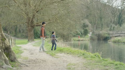 4K Happy father & son in the countryside skimming stones on river