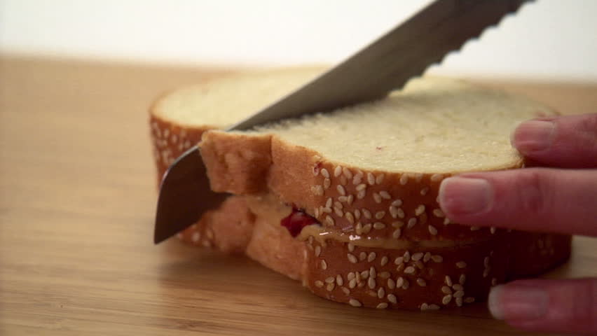 Woman cutting peanut butter and jelly sandwich