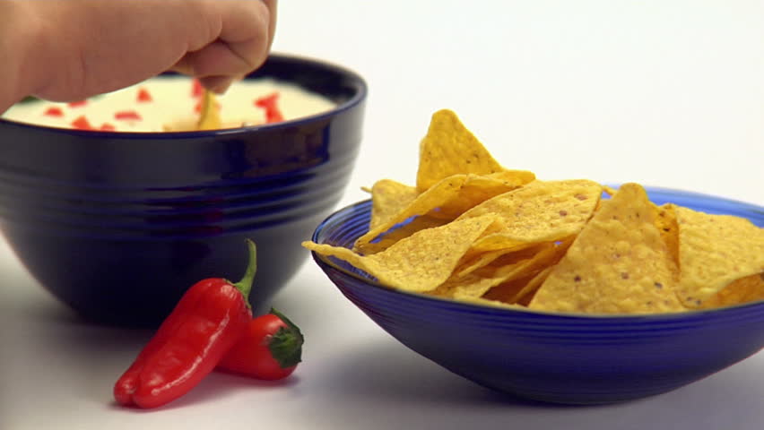 People dipping corn chips into guacamole dip