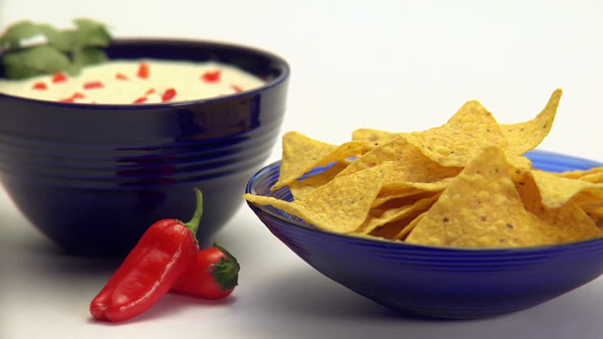 Person dipping corn chips into guacamole dip