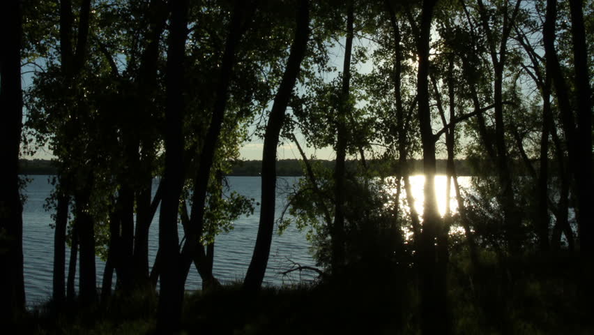 Majestic sunrise over a lake and through the trees. HD 1080p time lapse.