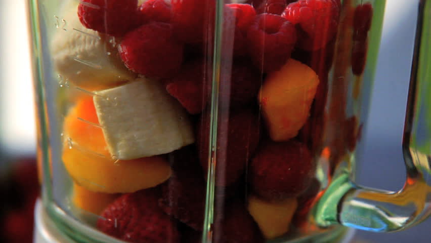 Juice being added to blender full of fruit and then blended