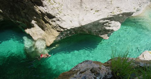 Top view Young woman swimming in river gorge Athletic swimmer girl relaxing in crystal clear blue water on bright sunny summer day enjoying nature outdoors