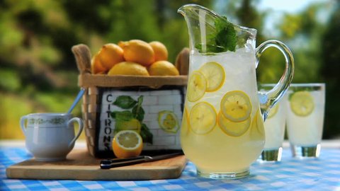 Man removing 2 glasses of lemonade from table with Pitcher of lemonade outside - Βίντεο στοκ