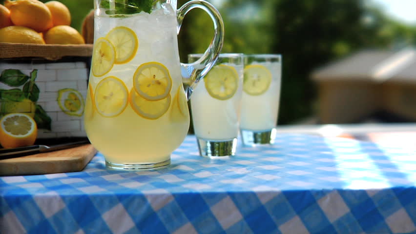 Pitcher of lemonade and glasses on table outside