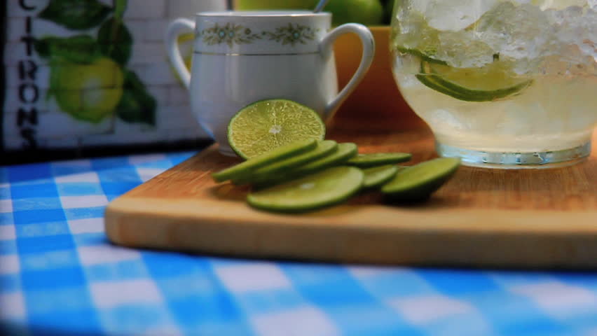 Man adding sliced limes to pitcher of ice