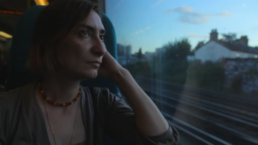 Middle aged woman sitting near the window in the train, looking and thinking about the future.