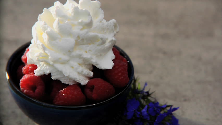Bowl of raspberries with whipped cream and mint added