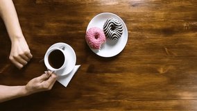 Young girl drinking coffee with donuts in cafe, top view, slow motion hd video