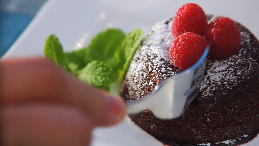 Cutting into chocolate lava cake with raspberries and mint