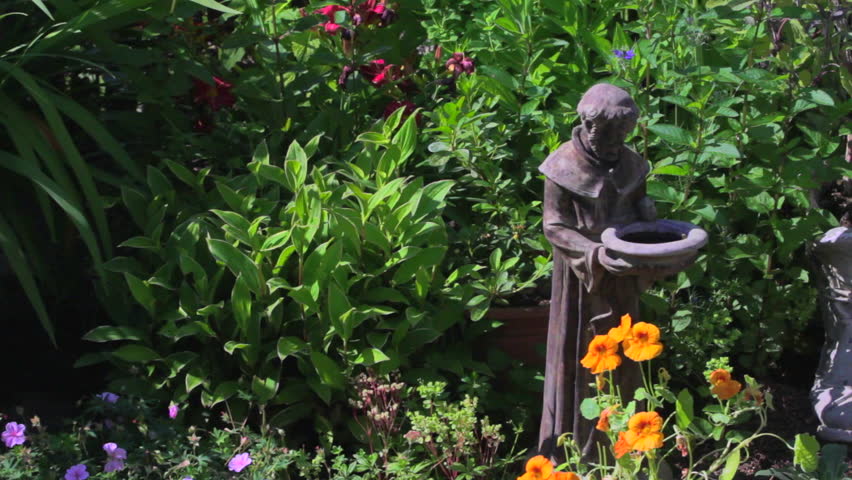 Pan over garden flowers and St Francis statue