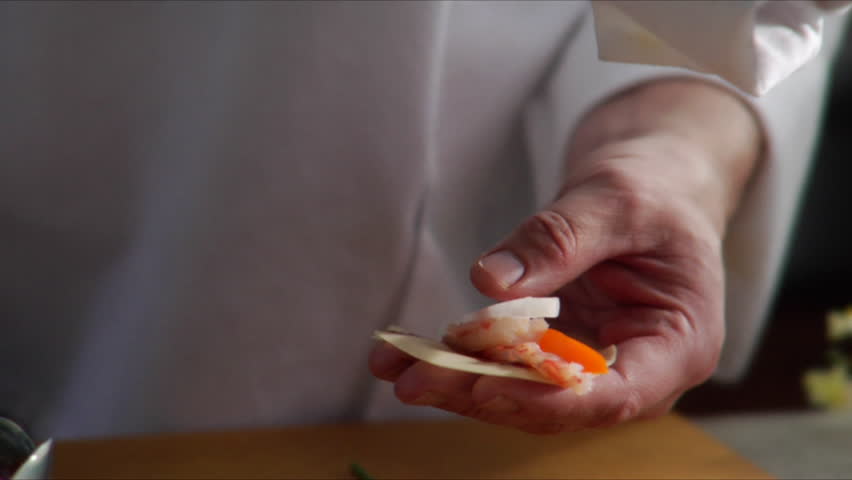 Chef prepares Asian shrimp appetizer and camera pan over as he places it on a