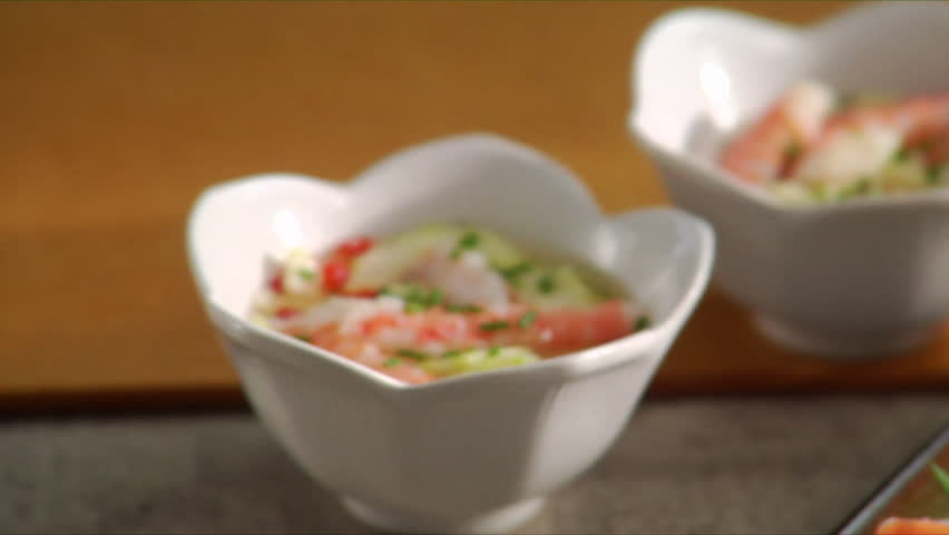 Close-up pan over cucumber salad as chef places four shrimp tempera onto serving