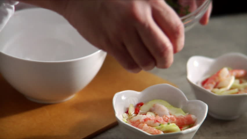 Slow pan over chef garnishing shrimp and cucumber salad.