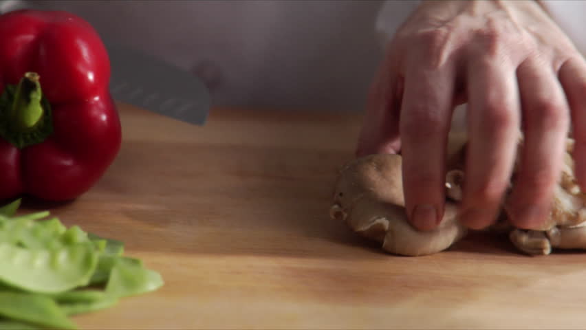 Close-up, lock down shot of chef chopping oyster mushroom.