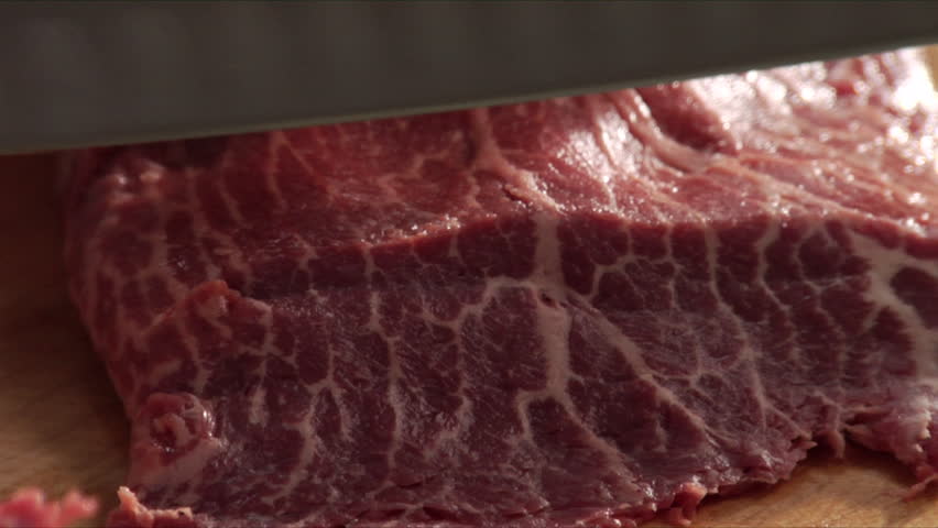 Extreme close-up of chef slicing steak.
