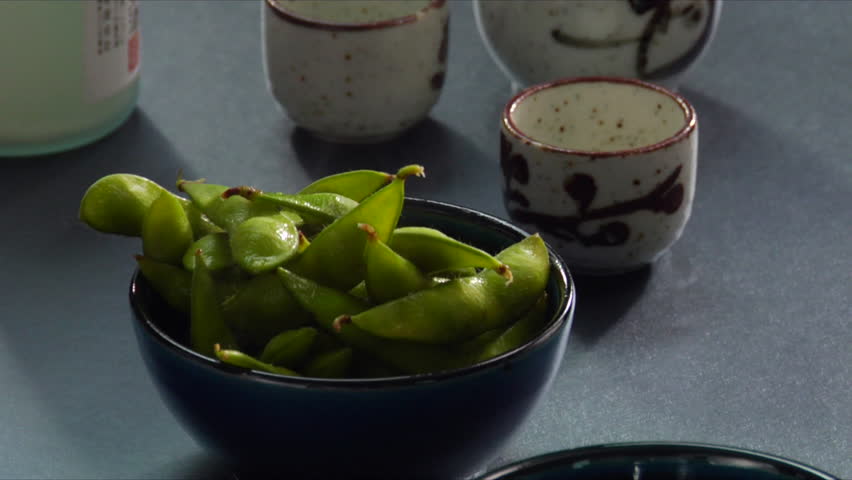 Close-up of steaming hot Edamame (soy beans) being placed into small serving