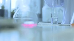 Scientist Pipetting Liquid Into Flask In Laboratory