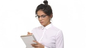 Serious businesswoman writing notes in notebook isolated on a white background