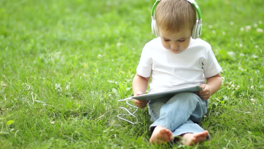 Boy with a tablet PC in headphones outdoors
