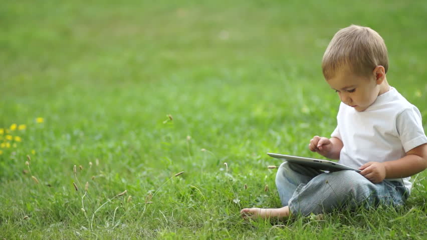 Child working with the Tablet PC sitting on the grass
