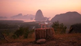 Copter Drone Taking Off in Park Against Beautiful Sunrise with Mountains on Background. Phang Nga, Thailand.