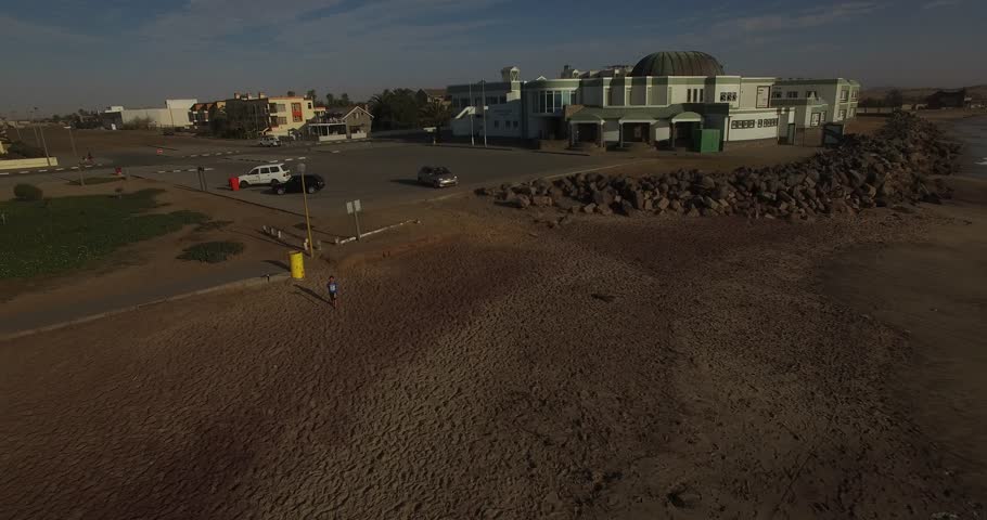 Drone video of view of Namibian Atlantic coastline, Swakopmund town buildings, beach, old pier, surf break point and landscape of ocean background of Swakopmund holiday resort at Namibia